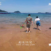 福建的海滩边海水真蓝，兄妹俩一起玩沙子