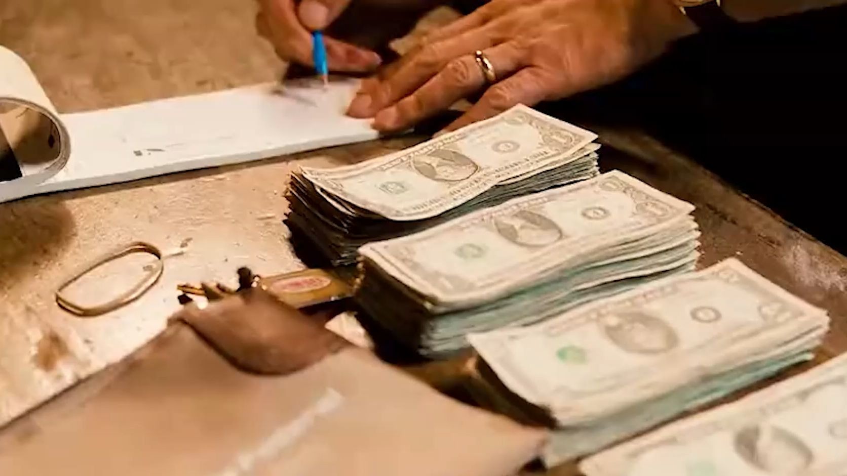 男人正在清点自己手中的钞票，每晚文森特都会在酒吧关门后去马路对面把钱存起来《堕落街传奇》