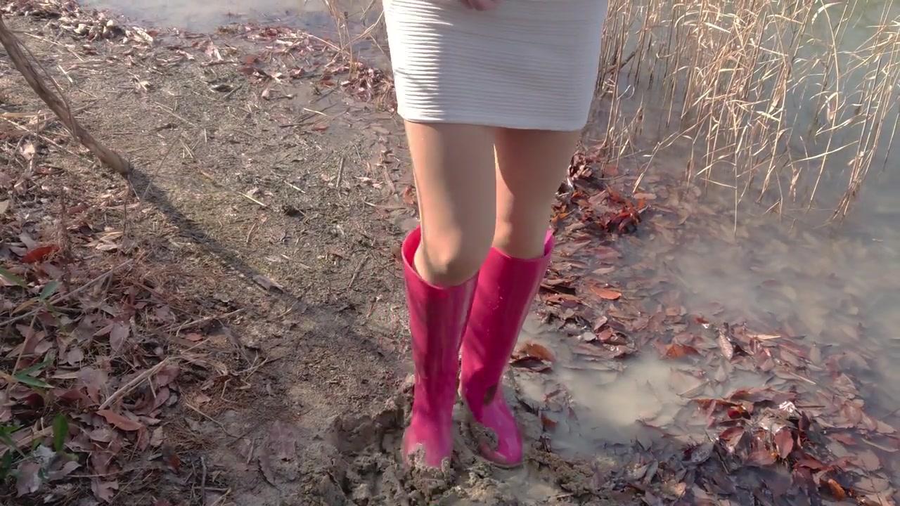 姑娘穿裙子粉红高筒雨靴水边踩泥
