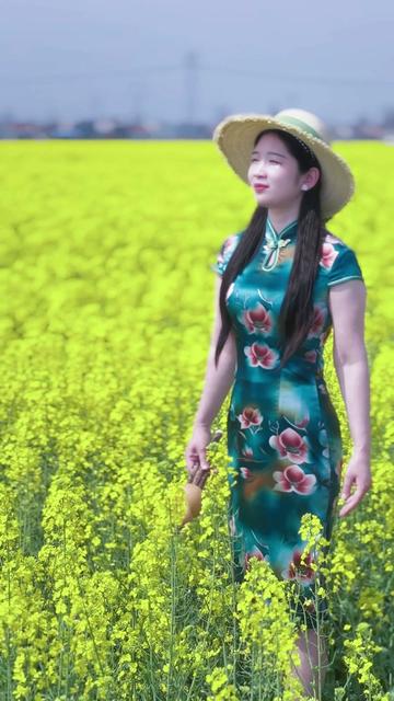 旗袍美女乡村油菜花地用c调葫芦丝演奏一曲经典歌曲《月光下的凤尾竹