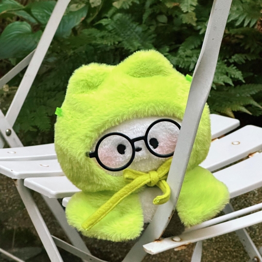 在白色椅子上的绿色小玩偶