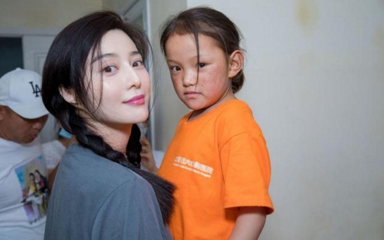 范冰冰现身做公益对镜头摆拍假笑抱孩子手都不敢搭背上