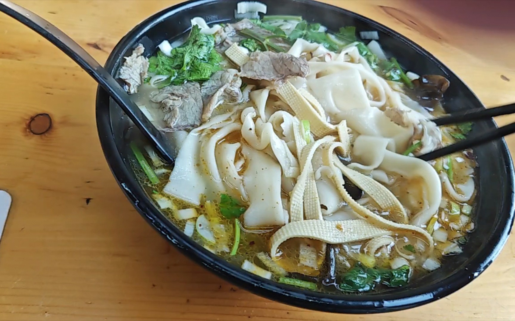 小伙在路边点了一份河南烩面,老板放了很多葱,骨汤很美味