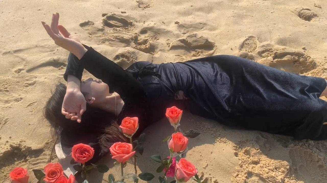 女子海边拍照,用花朵精心布景优雅躺沙滩,不料海浪来袭尖叫翻车