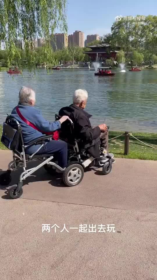 老爷爷骑着电动轮椅车带老奶奶逛兴庆公园