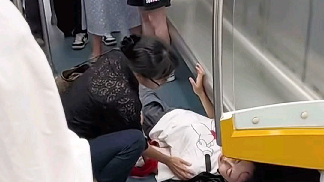 地铁上发生的一幕,一女子晕倒在车厢里,其实只有一位女士帮忙,其他的