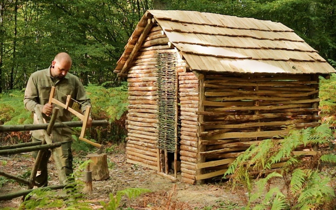 木屋用手工工具在樹林中建造有屋頂的庇護所