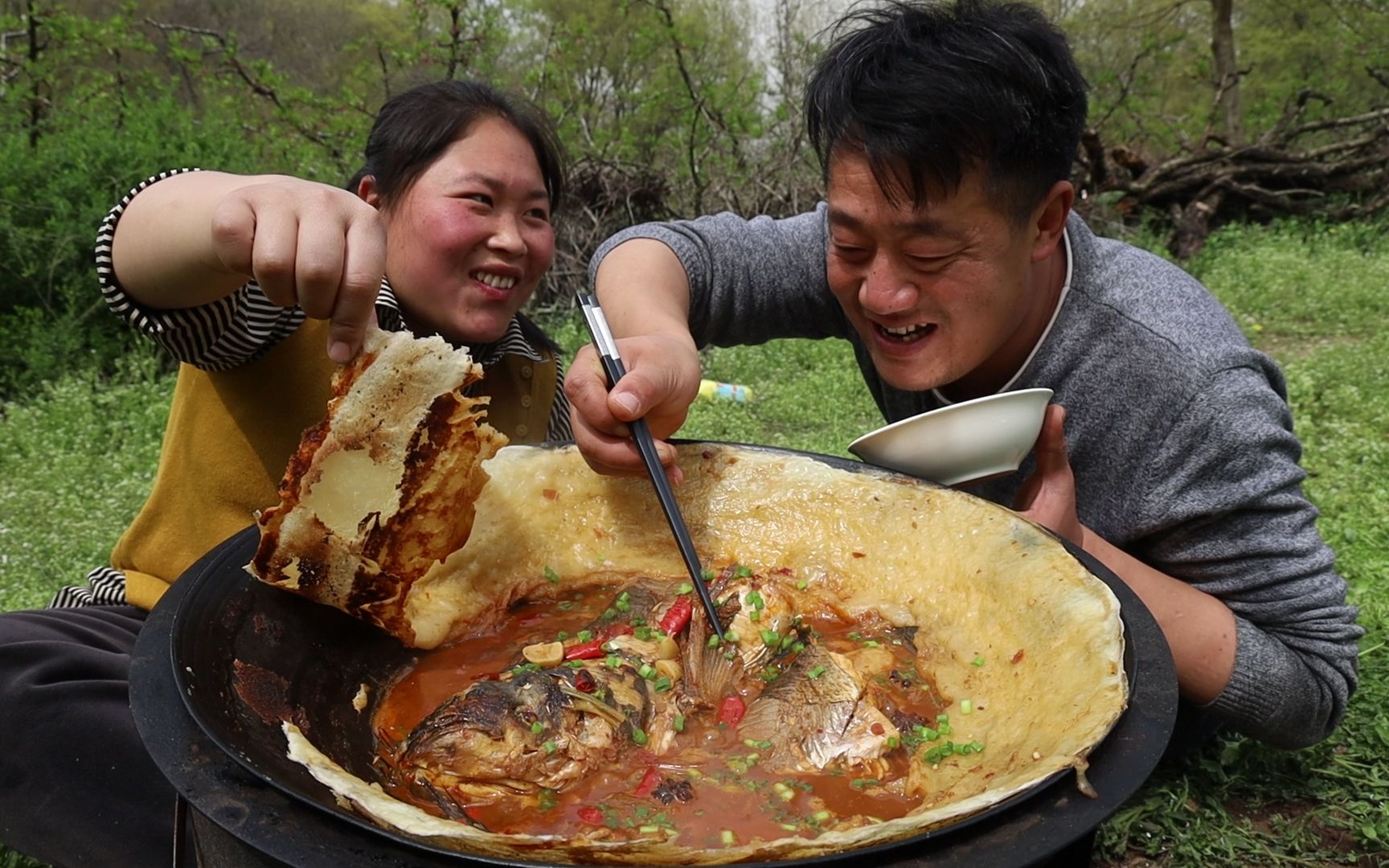 [图]春游踏青去处多，胖妹桃花树下享生活，铁锅炖鱼配饼，吃起来过瘾