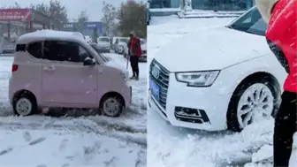 Скачать видео: 雪天车辆打滑难行，奥迪车主路边卑微铲雪，五菱萌娃轻飘划过亮了