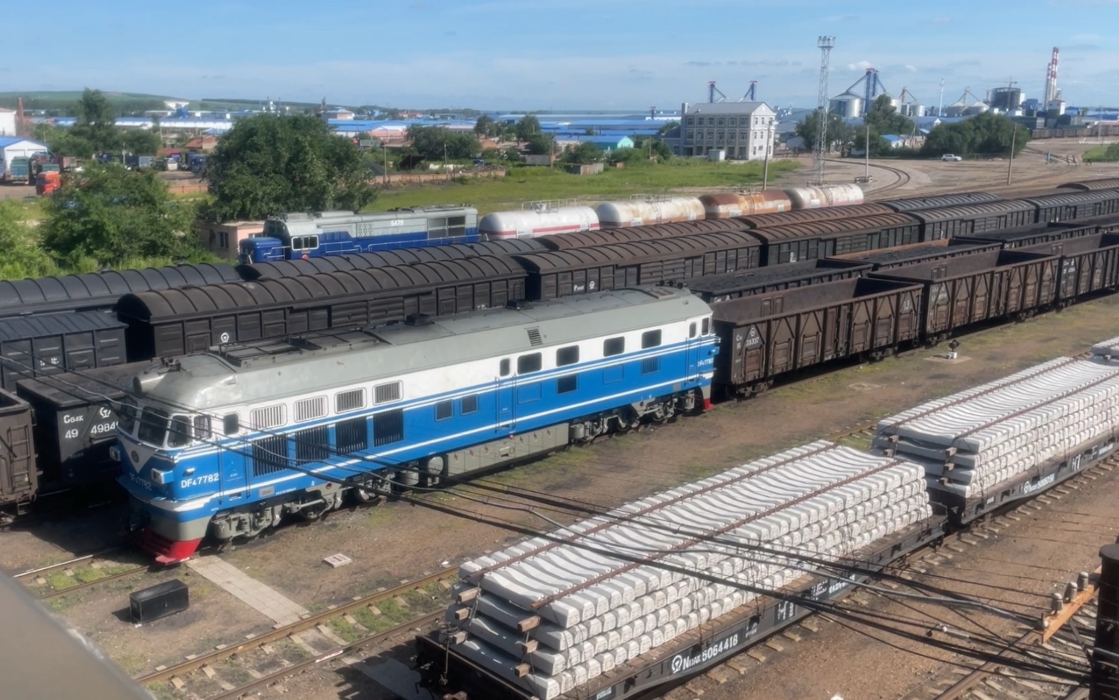 蓝白色涂装的df4b7782牵引26辆敞车编组的货物列车嫩江站鸣笛发车